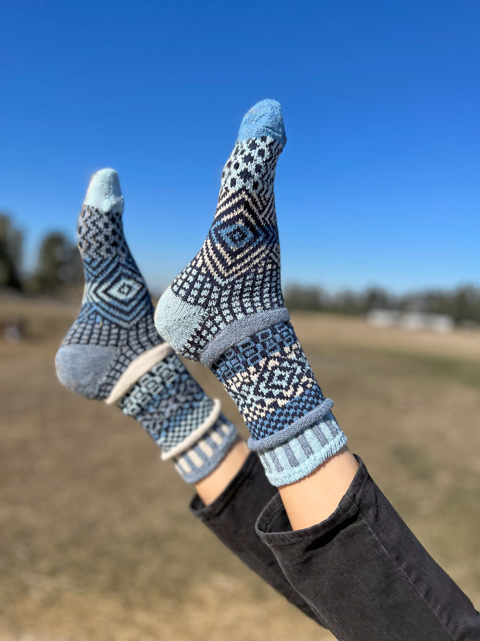 Azure Crew Socks with bold mismatched geometric knit patterns outdoors