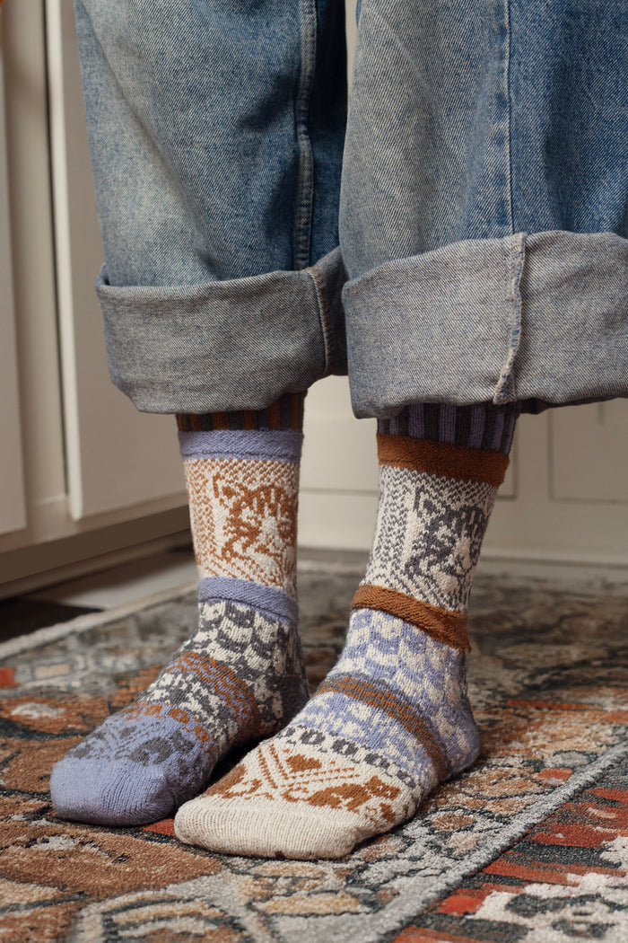 Person wearing cat pattern crew socks indoors with rolled jeans