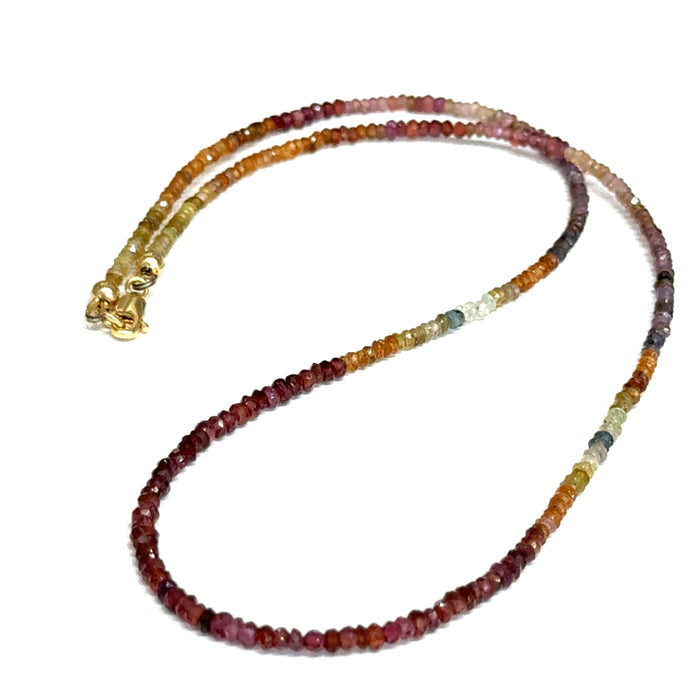 Close-up of natural brown sapphire beads showing honey amber to chocolate color variations, on a white background, in a long overview.