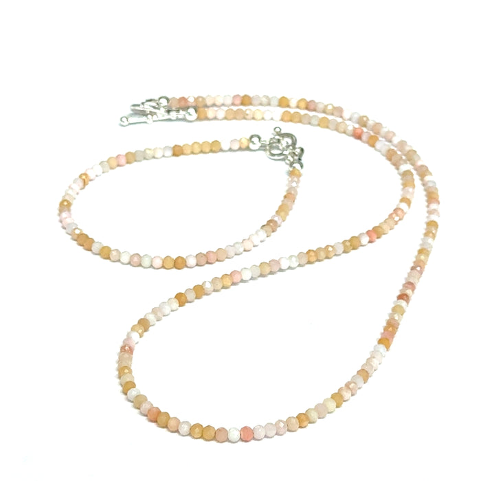 Close-up of faceted pink opal gemstone beads on delicate beaded bracelet with handcrafted toggle with its matching necklace on a white background, front view.