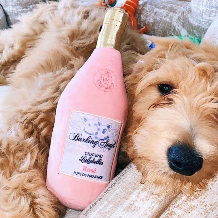 Dog with a pink bottle-shaped plush toy featuring Barking Angel.