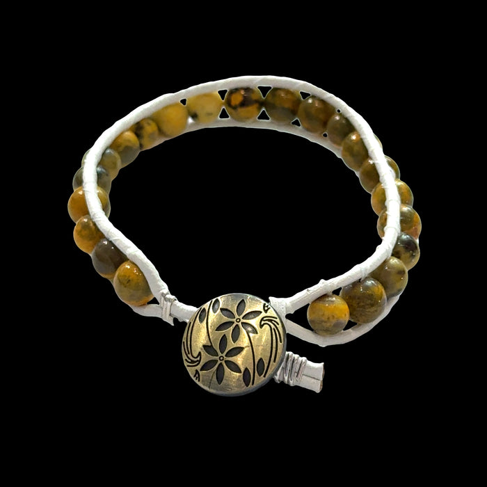 Close-up of genuine Bumblebee Jasper beads showing vibrant yellow and black volcanic patterns, 6mm gemstone bracelet, on a black background, back view.