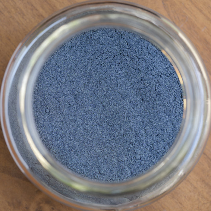Close-up of a glass jar filled with blue powder on a wooden surface