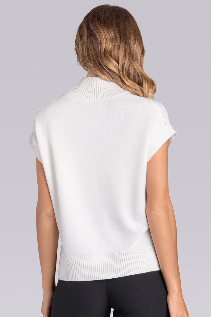 Model wearing the Charisma Off White short sleeve knit shirt, styled with black pants.
