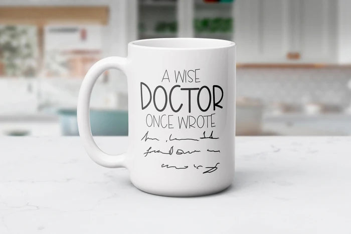 White Doctor’s Orders ceramic coffee mug featuring “A Wise Doctor Once Wrote” with a handwritten prescription-style design, available in 11 oz and 15 oz sizes.