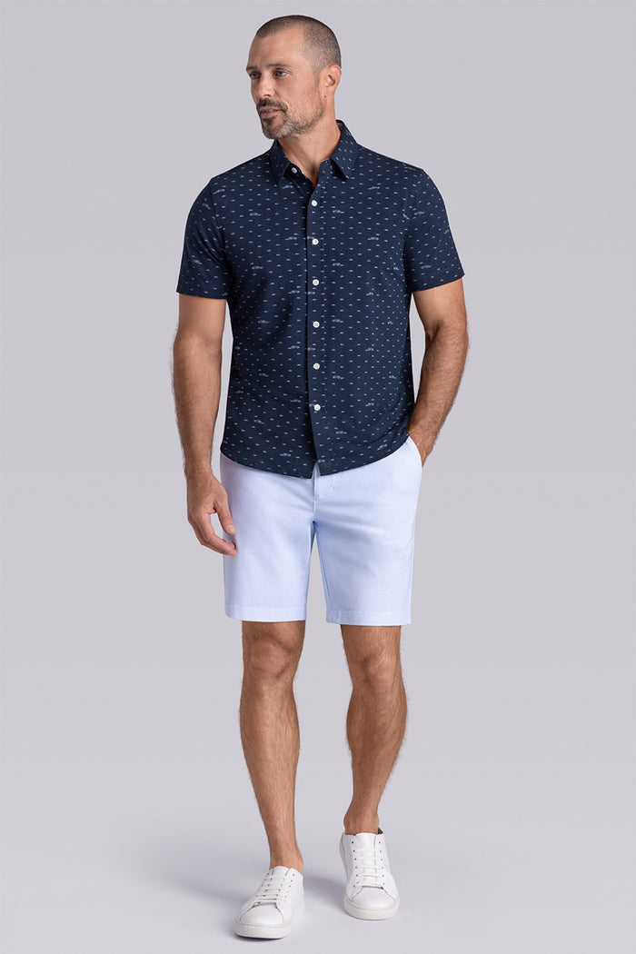 Model wearing Drift Legion Blue Heather short sleeve car print shirt, styled with white shorts