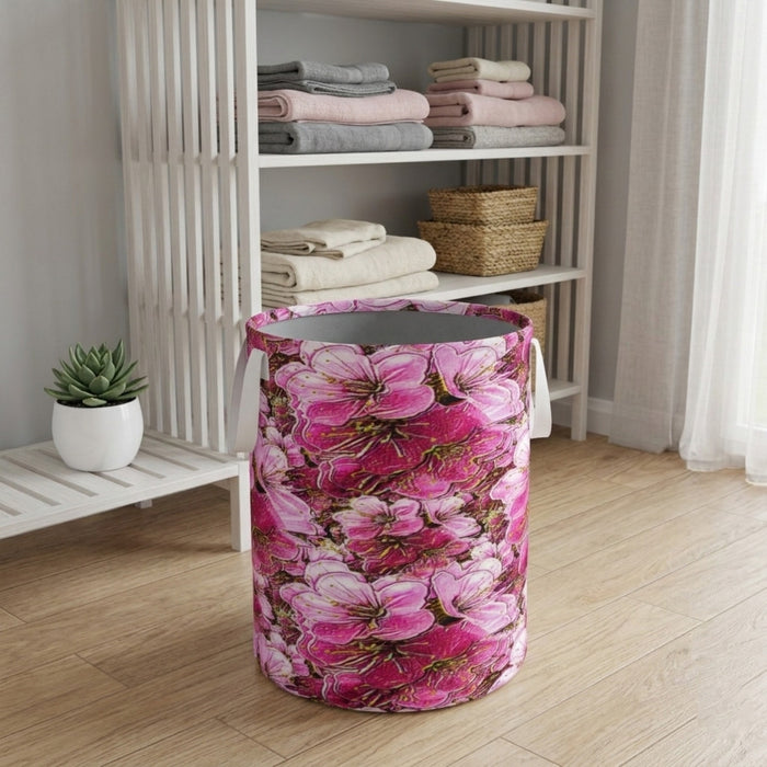 A vibrant pink floral laundry basket with a charcoal interior sits in a clean, wooden-floored home organization space with stacked towels and a plant.