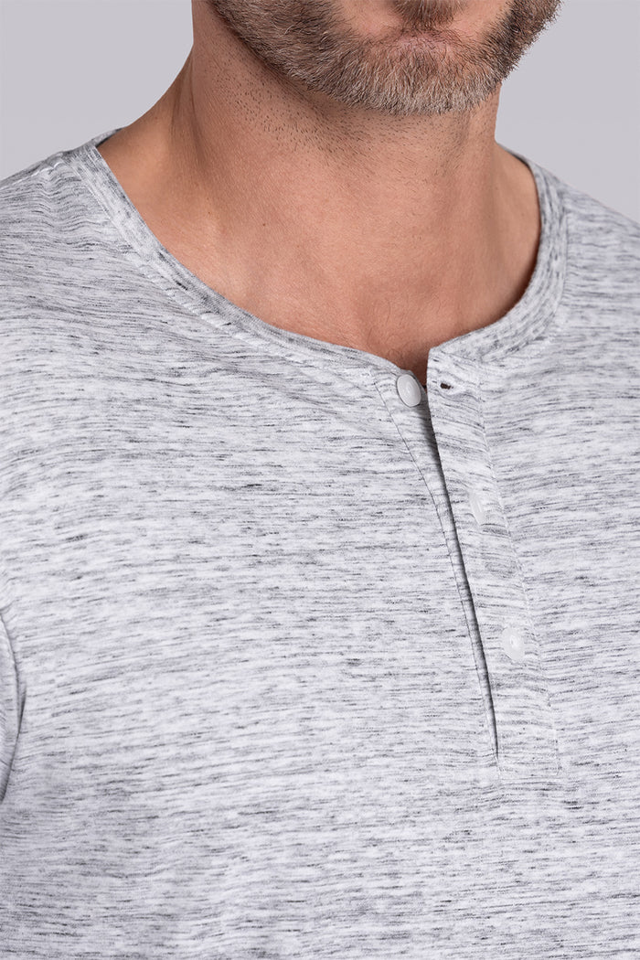 Model wearing Elemental Bone White Heather long sleeve henley shirt, styled with black pants.