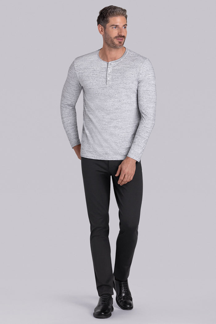 Model wearing Elemental Bone White Heather long sleeve henley shirt, styled with black pants.