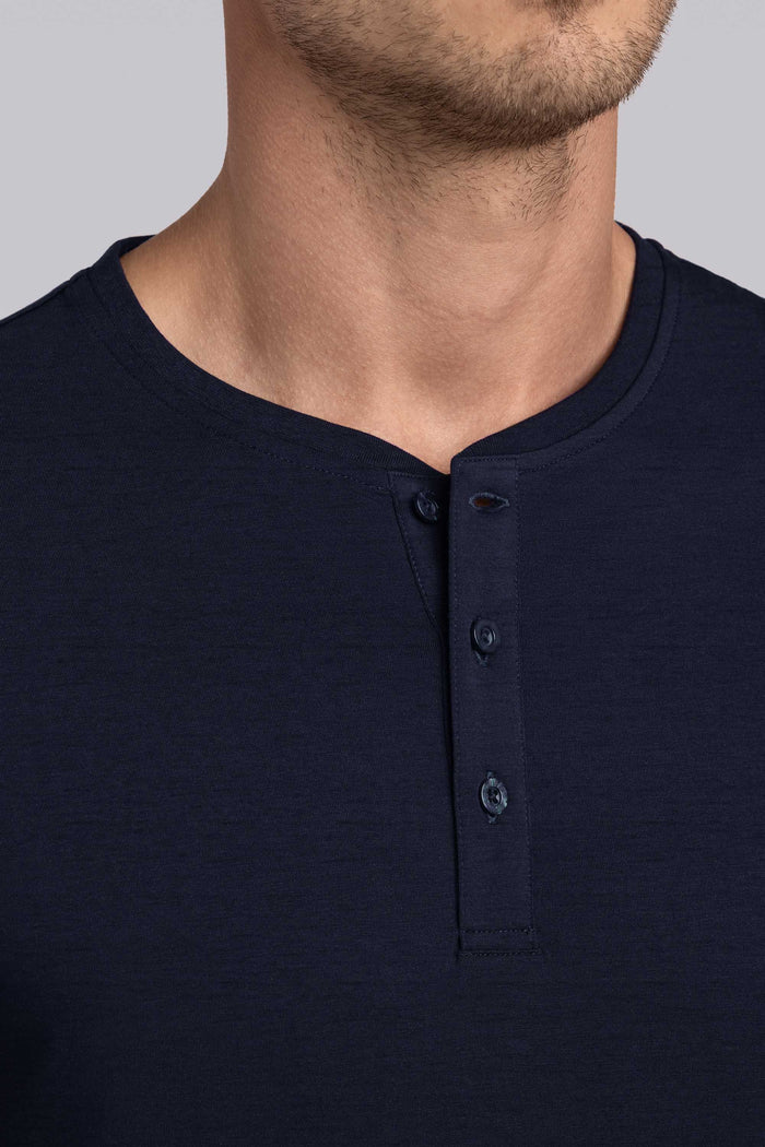 Model wearing Elemental Navy long sleeve henley shirt, styled with black pants.