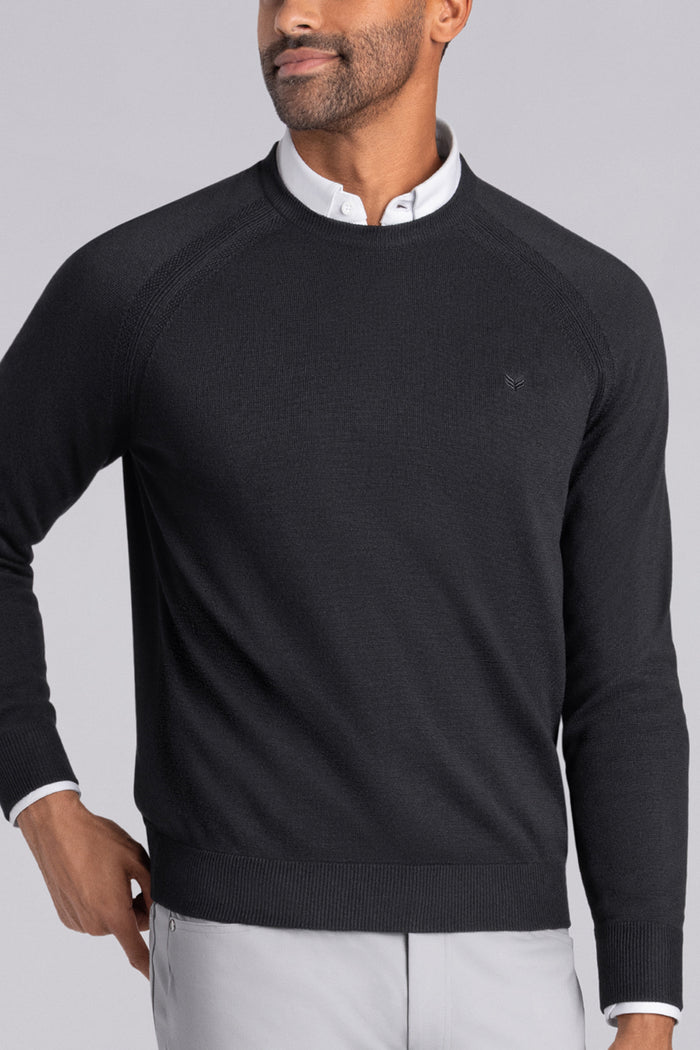 Model wearing Exemplary Black raglan sleeve crewneck sweater, styled with light grey slacks.