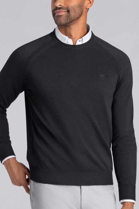 Model wearing Exemplary Black raglan sleeve crewneck sweater, styled with light grey slacks.