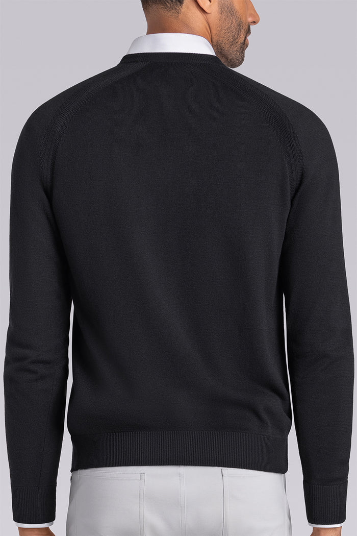 Model wearing Exemplary Black raglan sleeve crewneck sweater, styled with light grey slacks.