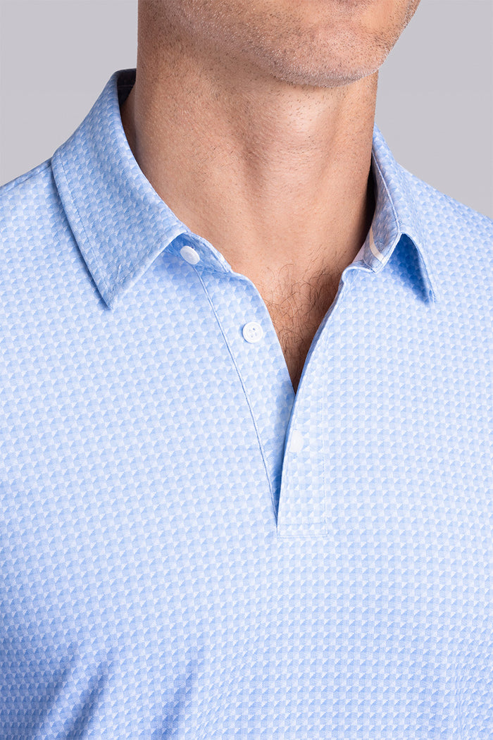Model wearing Flourish Ocean Blue short sleeve geo print polo, styled with black shorts.