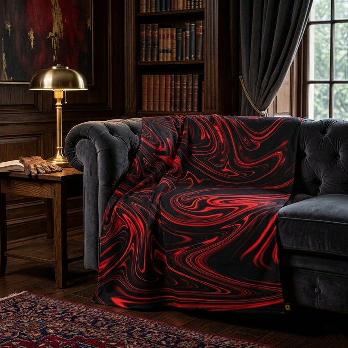 A black and red swirl pattern blanket draped over a dark grey tufted sofa in a moody, wood-paneled study with a brass lamp and bookshelves.