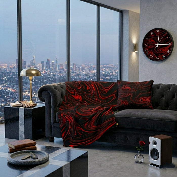 A modern penthouse living room featuring a matching black and red swirl blanket, pillow, and wall clock, with a cityscape view through large windows.