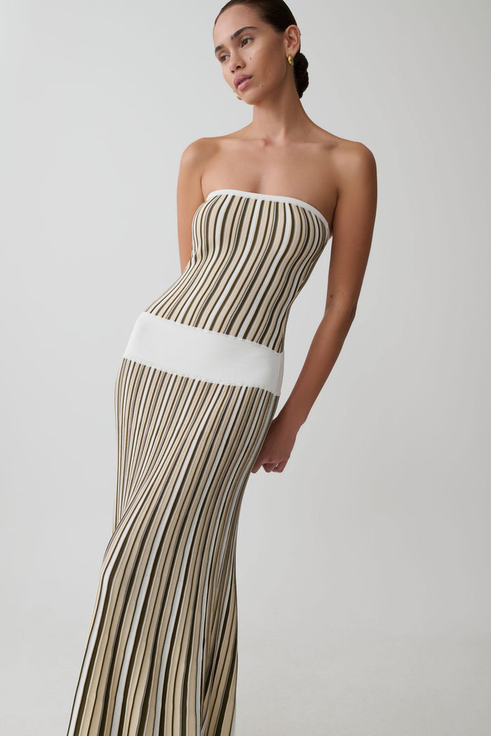 Woman wearing a strapless, long, pleated dress with a white wasitband.