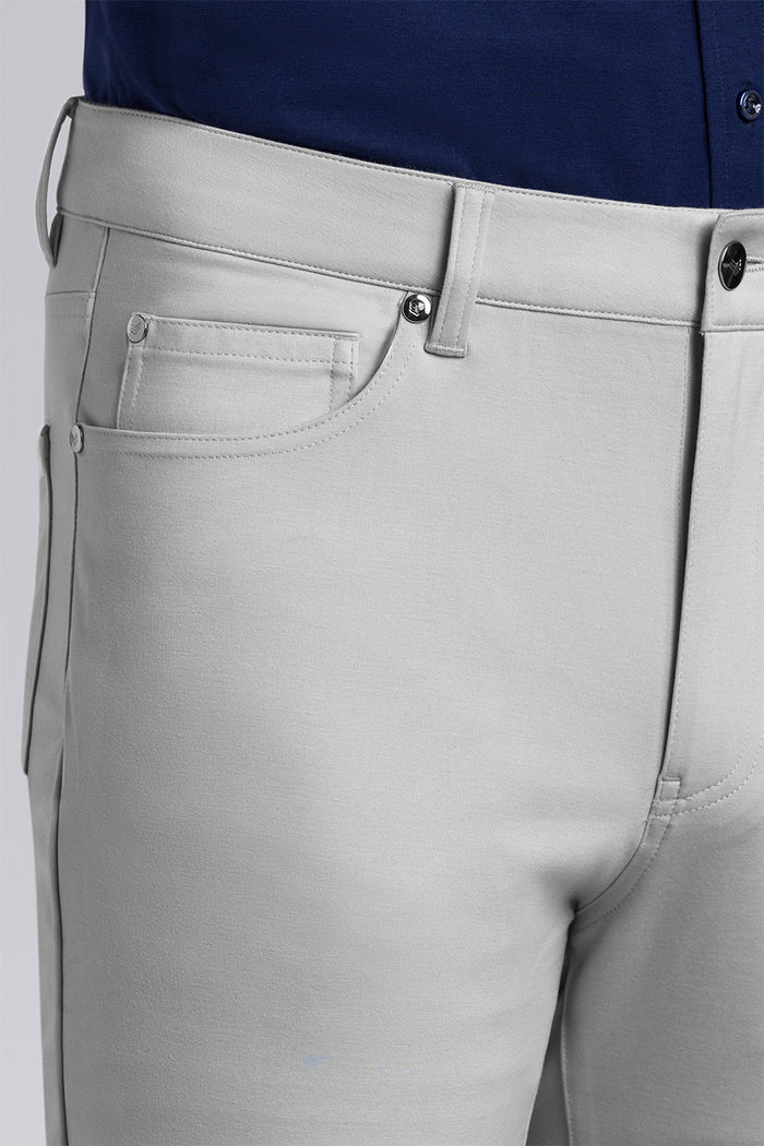 Model wearing Kinetic Light Grey dress slacks pants, styled with comfortable navy shirt