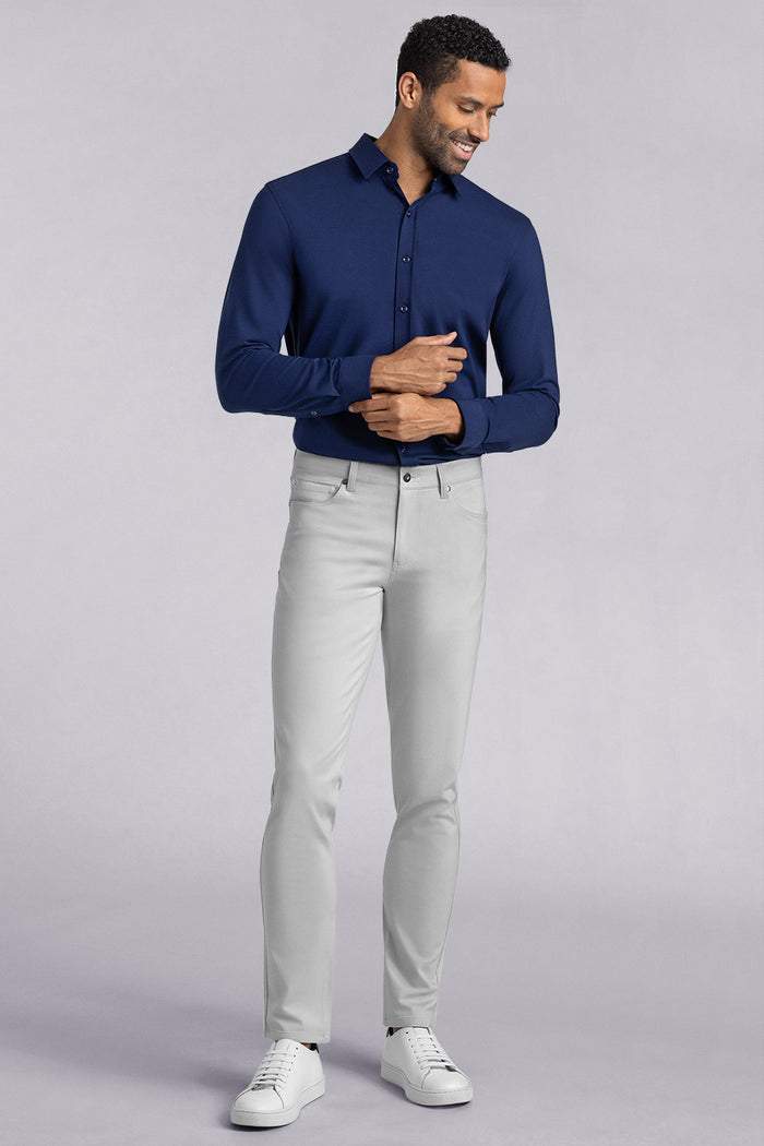 Model wearing Kinetic Light Grey dress slacks pants, styled with comfortable navy shirt