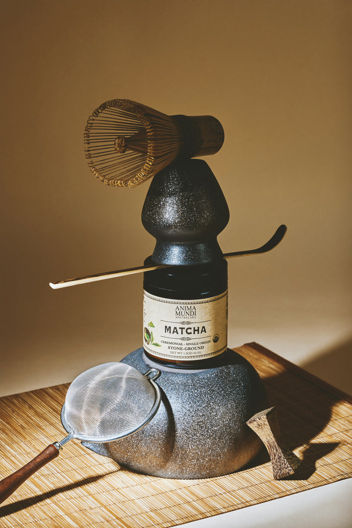 Matcha preparation set with a bottle labeled 'Andrea Munari' on a wooden surface.