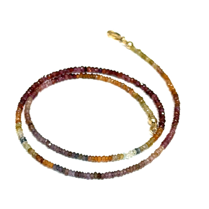 Close-up of natural brown sapphire beads showing honey amber to chocolate color variations, on a white background,  in a spiral front view.