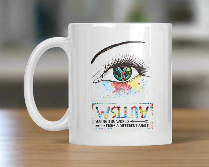 Colorful illustrated eye and butterfly inspirational coffee mug with watercolor splash details.