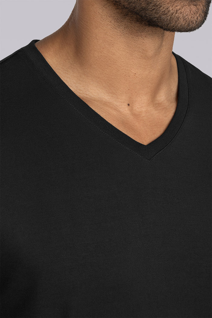 Model wearing Quintessential Black short sleeve v-neck shirt, styled with white pants
