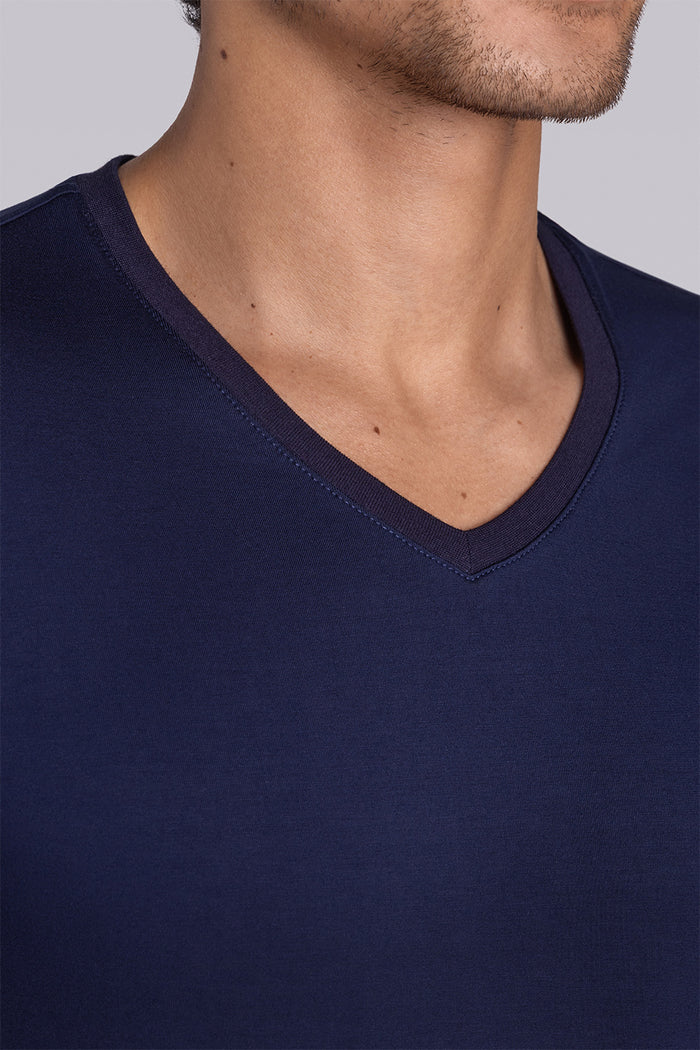 Model wearing Quintessential Monaco Blue short sleeve v-neck shirt, styled with white shorts