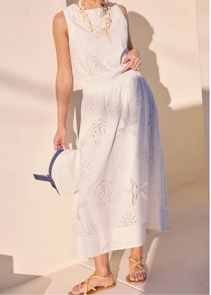 Woman in a white dress holding a blue bag against a light background