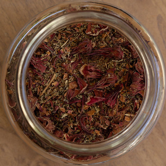 Glass jar filled with dried herbs on a wooden surface