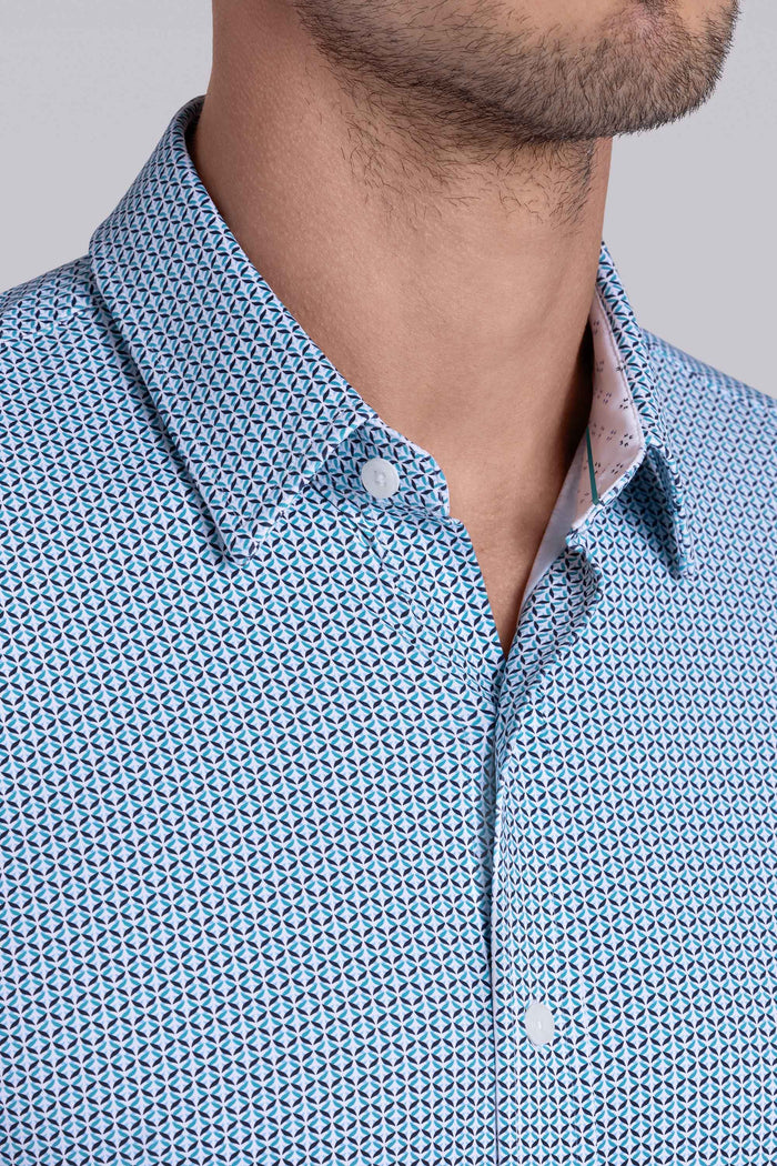 Model wearing Spry Seafoam long sleeve shirt with built in classic collar with geometric print, styled with jeans pants.