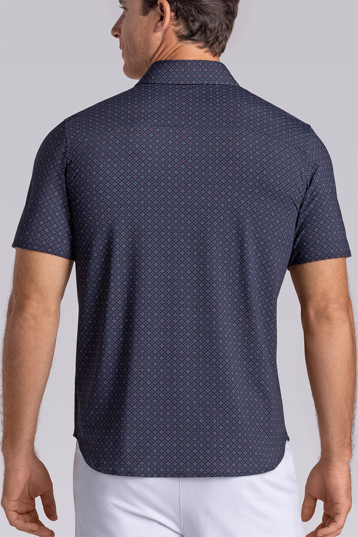 Model wearing Synergy Black Pink 6-way knit® short sleeve classic collar shirt, styled with white shorts.