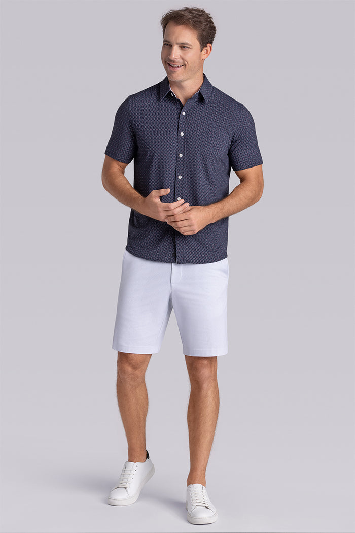 Model wearing Synergy Black Pink 6-way knit® short sleeve classic collar shirt, styled with white shorts.