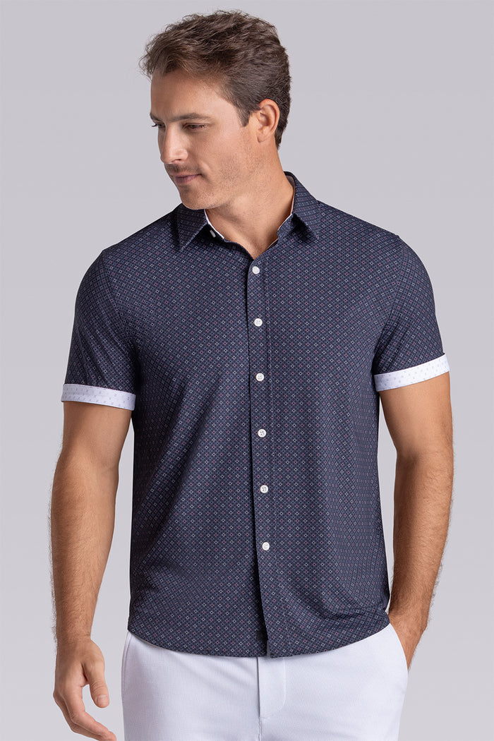 Model wearing Synergy Black Pink 6-way knit® short sleeve classic collar shirt, styled with white shorts.