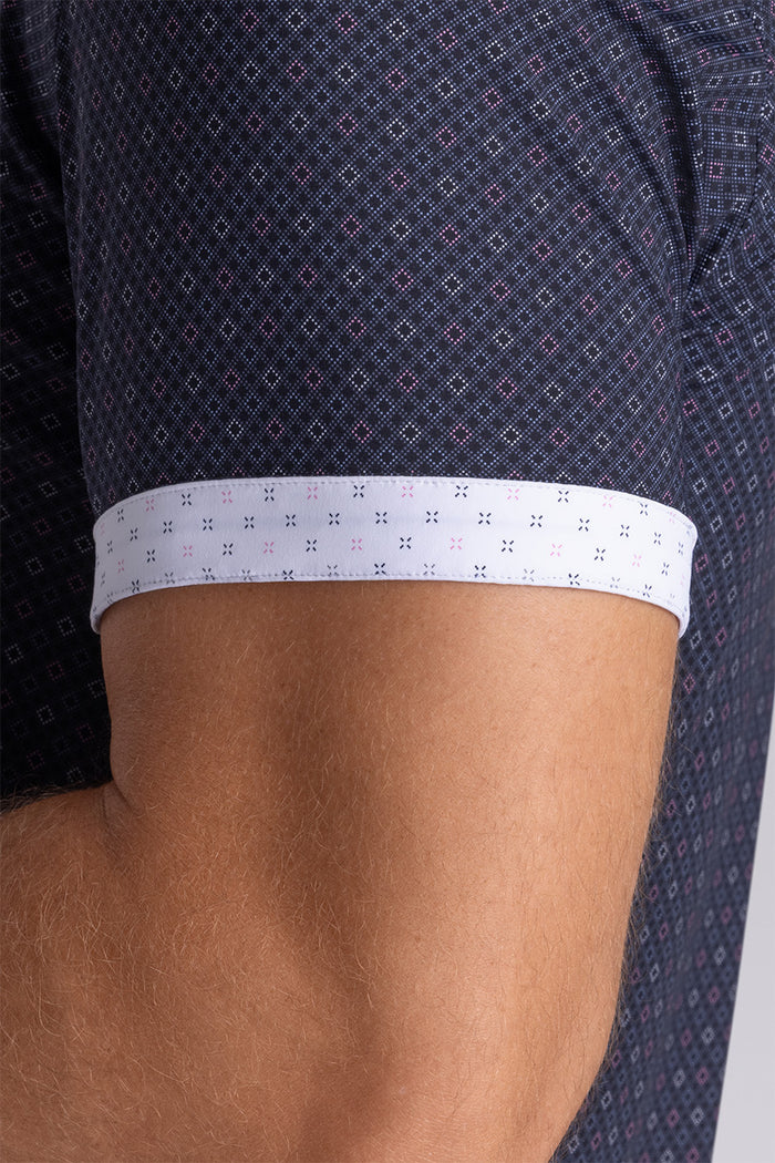 Model wearing Synergy Black Pink 6-way knit® short sleeve classic collar shirt, styled with white shorts.