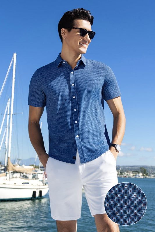 Model wearing Synergy Classic Blue 6-way knit® short sleeve classic collar shirt, styled with white shorts.