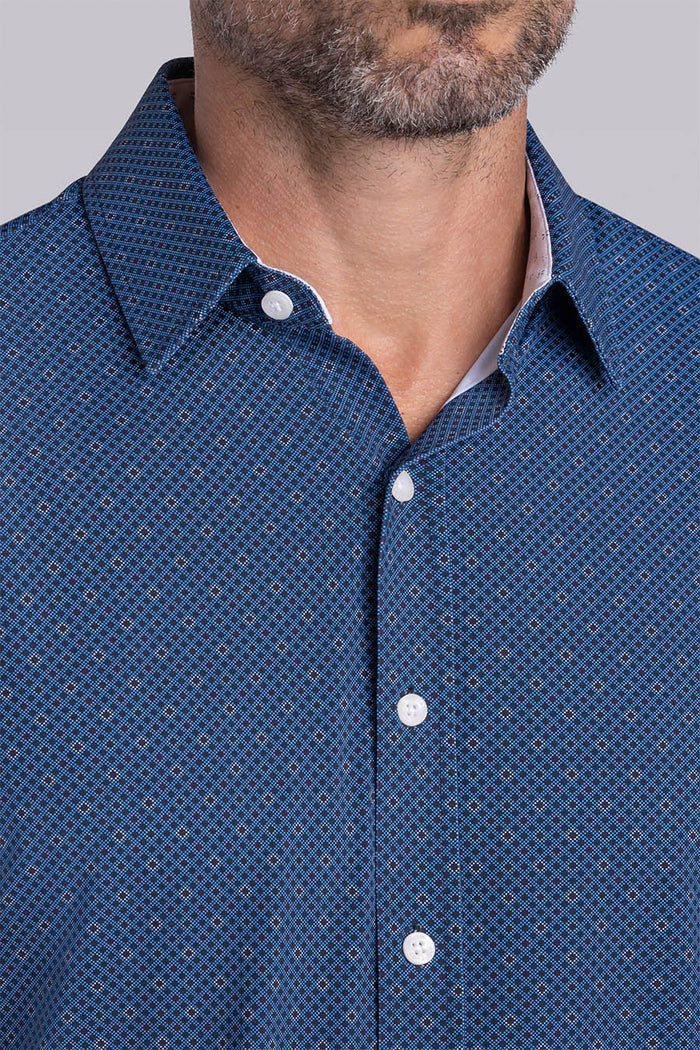 Model wearing Synergy Classic Blue 6-way knit® short sleeve classic collar shirt, styled with white shorts.