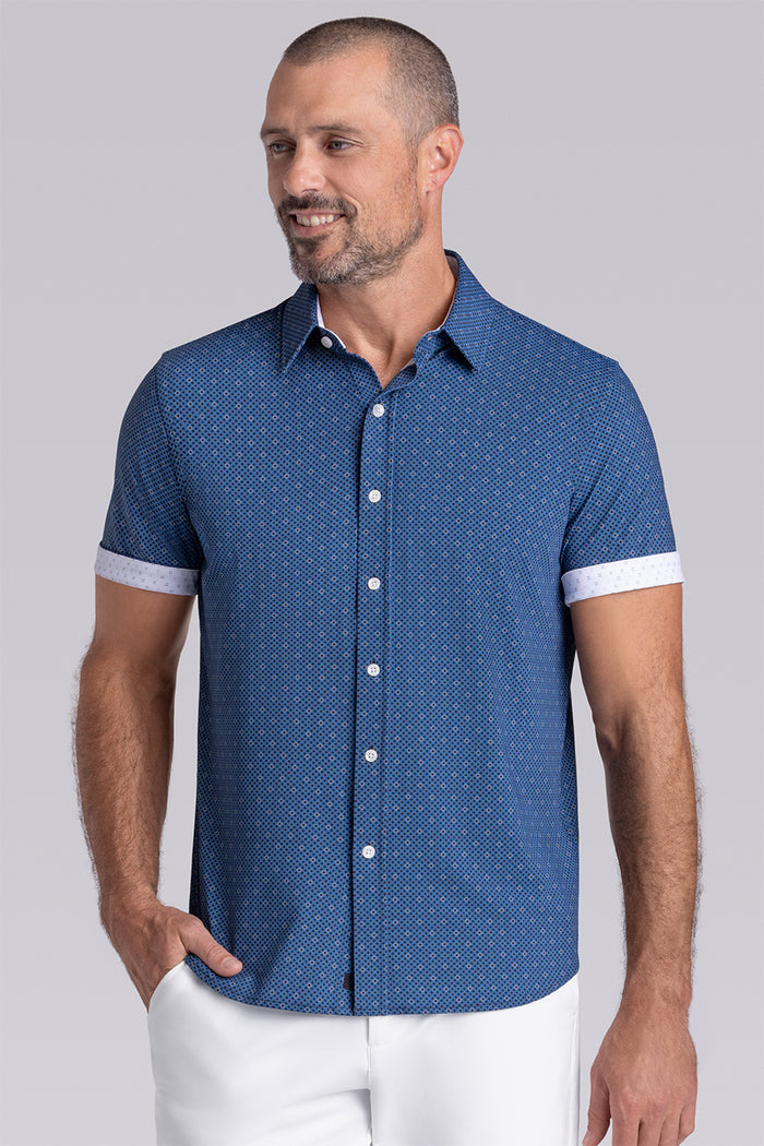 Model wearing Synergy Classic Blue 6-way knit® short sleeve classic collar shirt, styled with white shorts.