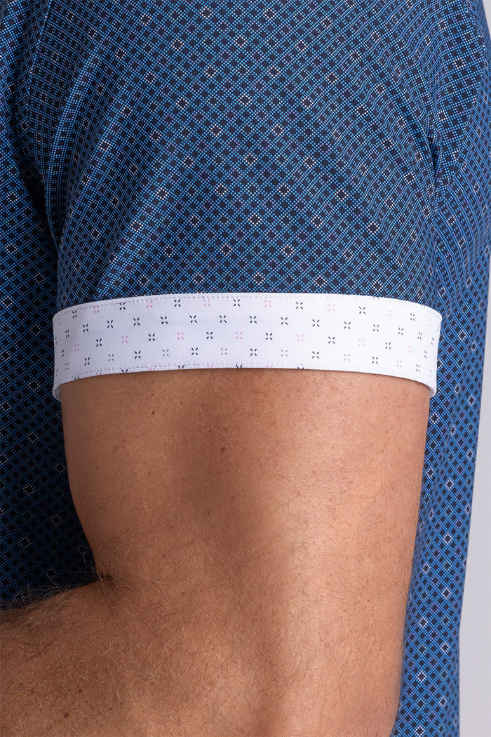 Model wearing Synergy Classic Blue 6-way knit® short sleeve classic collar shirt, styled with white shorts.