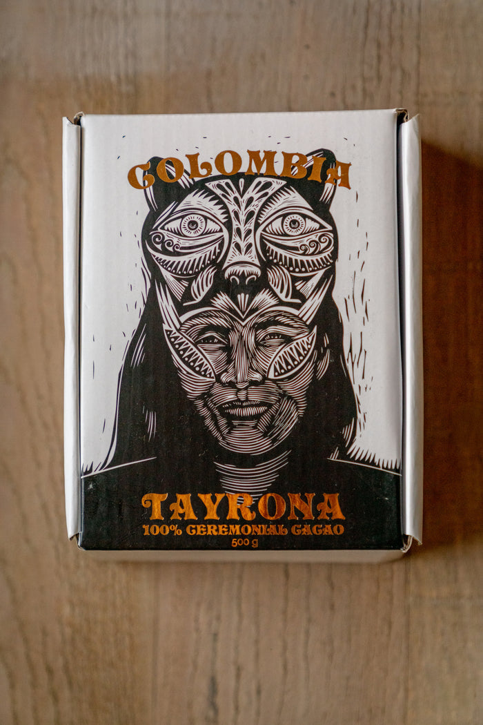 Tayrona Colombia packaging with a stylized face design on a wooden surface