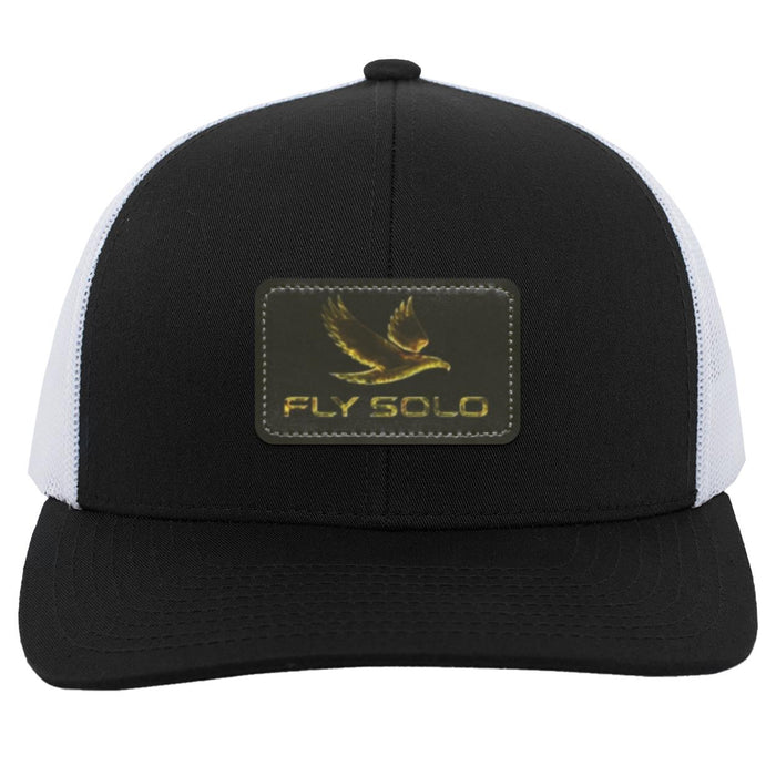 Front product shot of the black and white Fly Solo trucker snapback featuring the signature gold eagle leather patch.