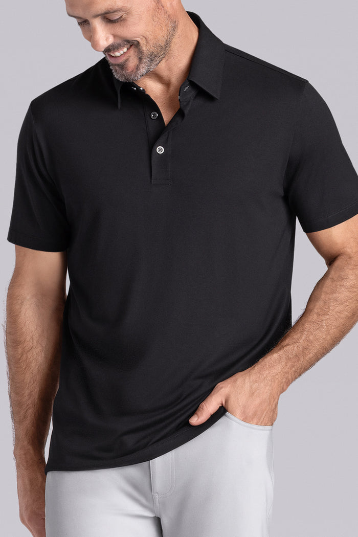 Model wearing Vital Black Icy Bamboo® short sleeve polo, styled with white pants.