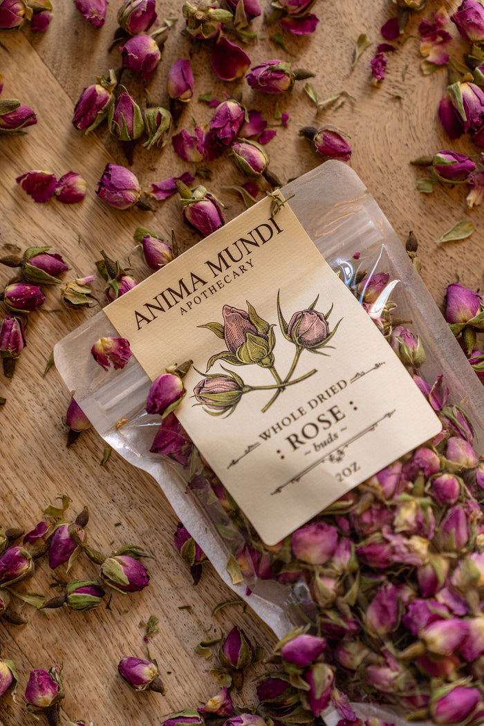 Packaged rose buds with Anima Mundi label on a wooden surface with dried roses.