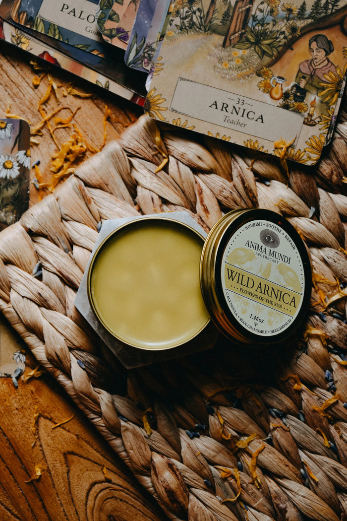 Two containers of Wild Arnica cream on a woven mat with a blurred background